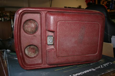 1985 Ford F-150 - This red center console features dual cup holders and a lockable compartment, likely from an older truck.