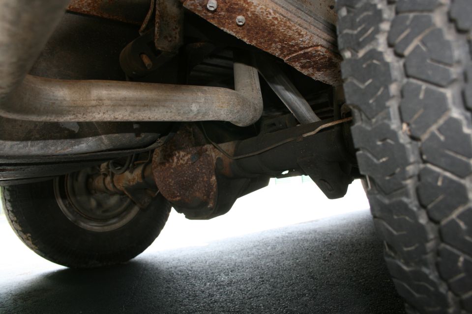 Underside view of a truck's rear axle, exhaust, and tire