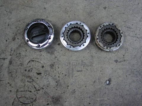 1981 Ford Bronco - Three metal hubcaps are laid out on a concrete surface, one with visible text indicating 4x4 and FREE functionality.