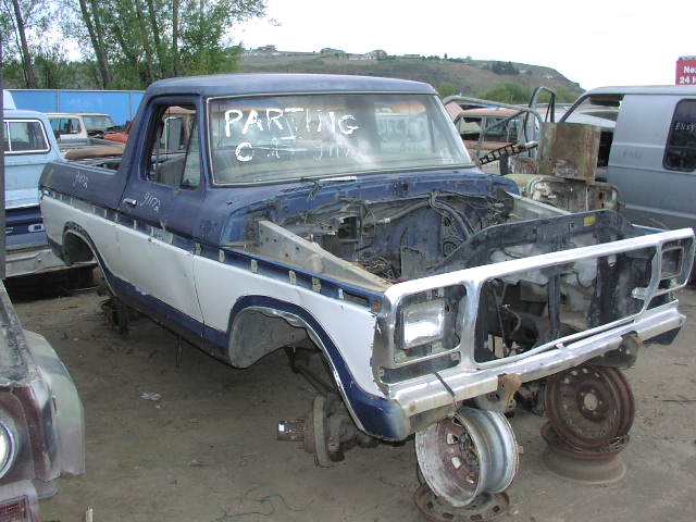 Blue and white Ford pickup being parted out in a salvage yard