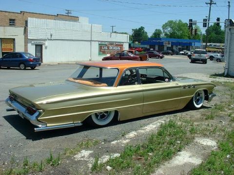 1972 Ford Ranchero - A customized gold sedan with an orange roof sits low to the ground on a sunny day.