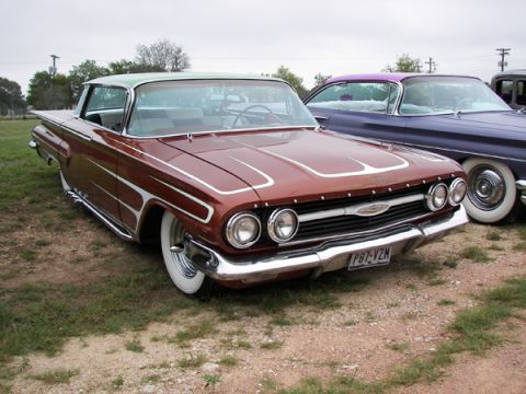 1972 Ford Ranchero - A classic brown 1960 Chevrolet Biscayne with custom pinstriping is parked next to a purple car.