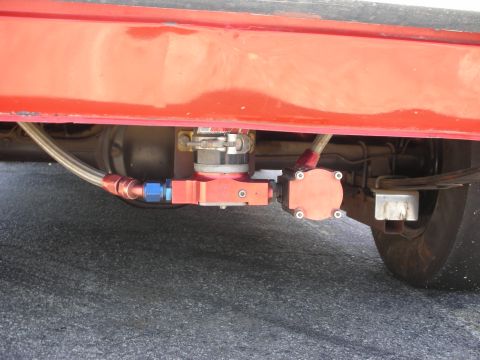 1992 Ford Crown Victoria - Close-up of a red vehicle's undercarriage, focusing on the fuel pump assembly and associated plumbing.