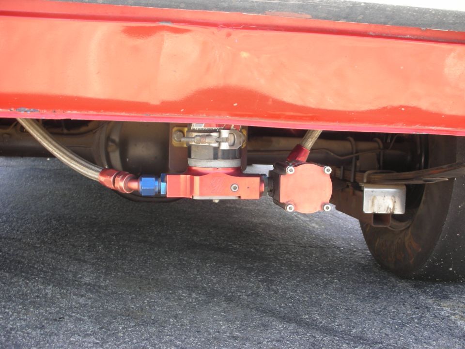 Red vehicle undercarriage with a red fuel pump assembly and braided fuel lines