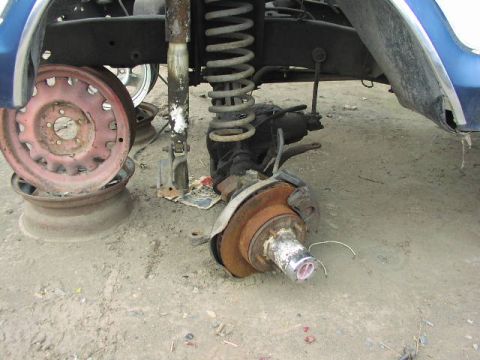 1981 Ford Bronco - This image shows the disassembled front suspension and wheel hub of a vehicle, likely in a junkyard setting.