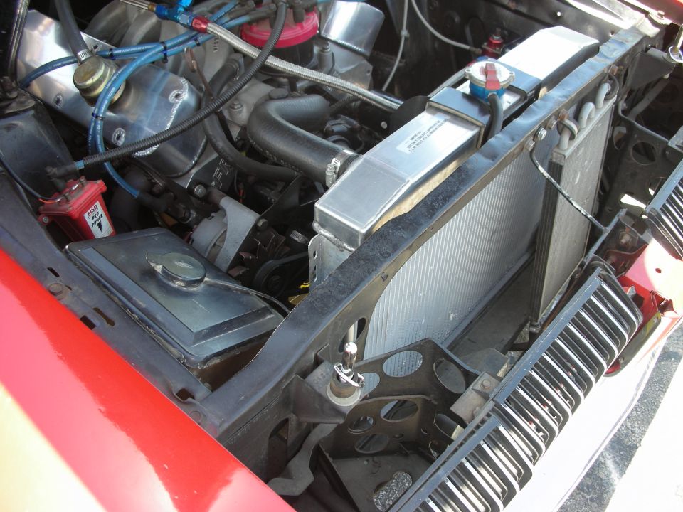 engine bay showing radiator, hoses, and engine components. Red fender visible