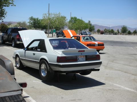 1992 Ford Crown Victoria - A gray 1987 Ford Mustang coupe is parked with its hood open, while an orange Mustang is behind it.