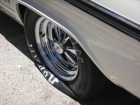 1992 Ford Crown Victoria - A flat tire on a silver vehicle with chrome wheels is visible from the side.