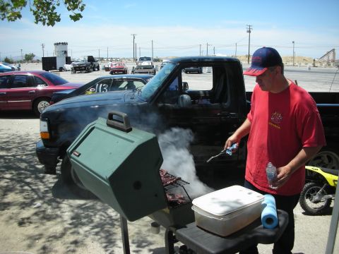 1992 Ford Crown Victoria - A man grills food in front of a black pickup truck at an outdoor event.