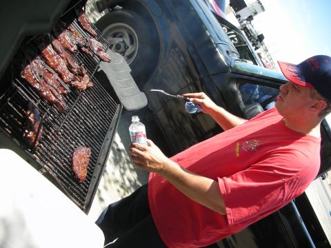 1992 Ford Crown Victoria - Man grilling ribs next to a black SUV.