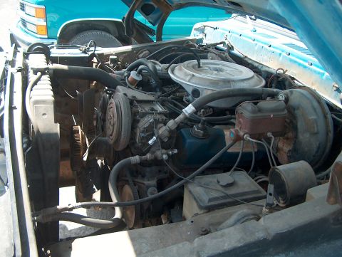 1978 Ford Bronco - Close-up view of a vehicle's engine bay, showing various components and another vehicle behind it.