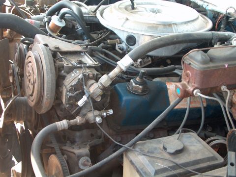 1978 Ford Bronco - Close-up view of a vehicle's engine bay, showing various components like the AC compressor and brake fluid reservoir.