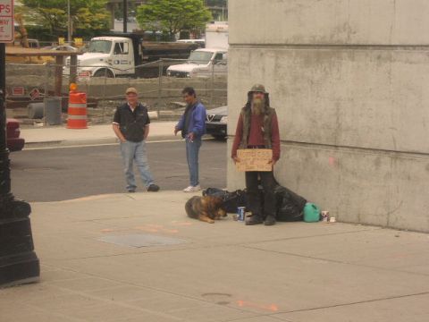 1981 Ford Bronco - A person holding a sign that reads "HOMELESS" stands next to a dog on a sidewalk.
