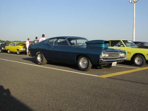 1981 Ford Bronco - A blue 1969 Ford Torino GT drag car with a large hood scoop is parked on asphalt, with other vehicles in the background.