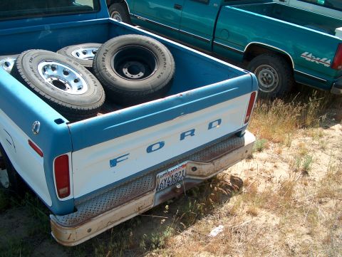 1978 Ford Bronco - Rear view of a vintage Ford pickup truck with spare tires loaded in the bed.