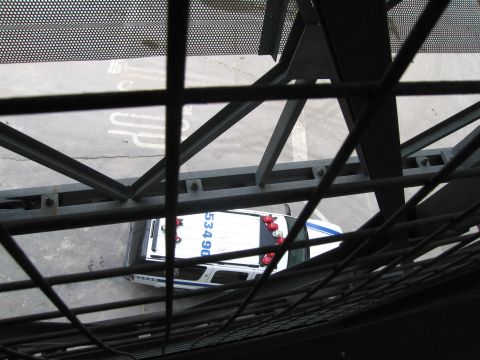1991 Ford LTD Crown Victoria - Looking down through metal grating, a white and blue police car numbered 5340 is parked on pavement below.