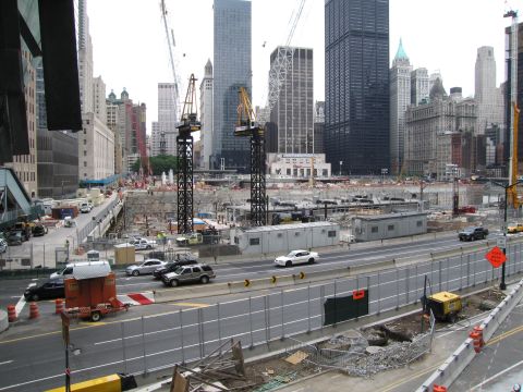 1991 Ford LTD Crown Victoria - vast urban construction pit with tower cranes and trailers sits behind a fence, framed by a dense city skyline.