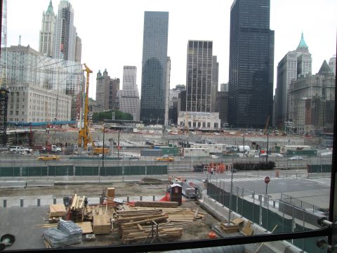 1991 Ford LTD Crown Victoria - Stacked lumber and fencing front a large construction site, with skyscrapers and a crane filling the skyline beyond.