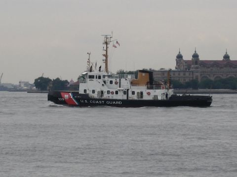 1991 Ford LTD Crown Victoria - black-hulled U.S. Coast Guard vessel crosses gray water with a large domed waterfront building behind it.