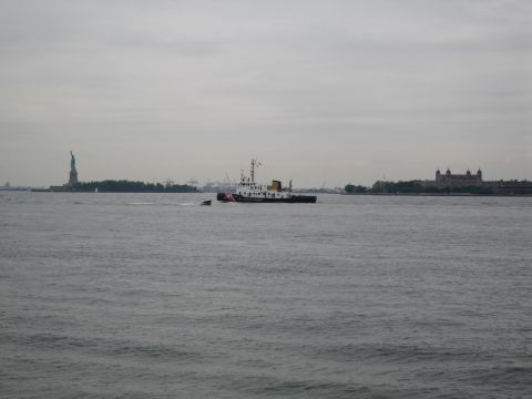 1991 Ford LTD Crown Victoria - small vessel sits on choppy gray water with the Statue of Liberty and a domed island building on the distant horizon.
