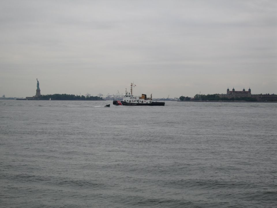 Distant boat on the water with the Statue of Liberty visible on the horizon