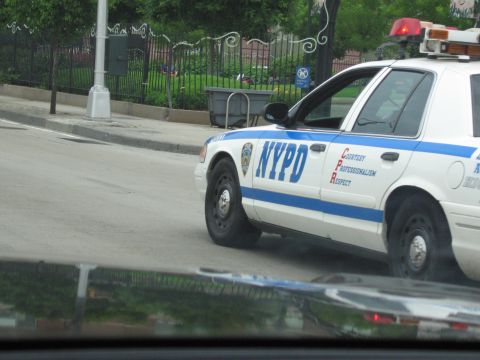 1991 Ford LTD Crown Victoria - white NYPD Crown Victoria police car marked Courtesy Professionalism Respect turns on a street, photographed over a car hood.