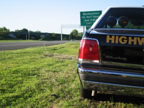 1991 Ford LTD Crown Victoria - close-up of a black sedan's taillight and chrome bumper shows HIGHWAY lettering and an LTD Crown Victoria badge on the rear.