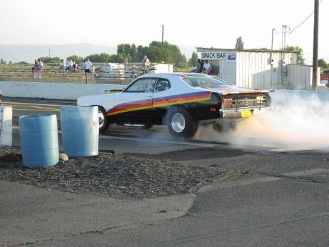 1981 Ford Bronco - A drag car performs a burnout at a race track, generating a large cloud of smoke.
