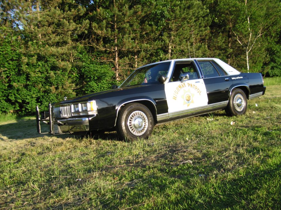 Highway Patrol sedan with push bar parked on grassy field