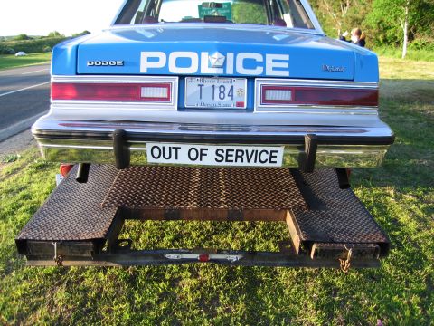 1991 Ford LTD Crown Victoria - Rear view of a blue Dodge Diplomat POLICE car on a flatbed trailer, marked OUT OF SERVICE with a Rhode Island plate T 184.