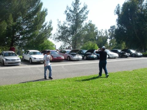 1991 Ford Taurus - A group of cars are parked in a lot, with two men in the foreground. One of the cars appears to be a 1991 Ford Taurus.