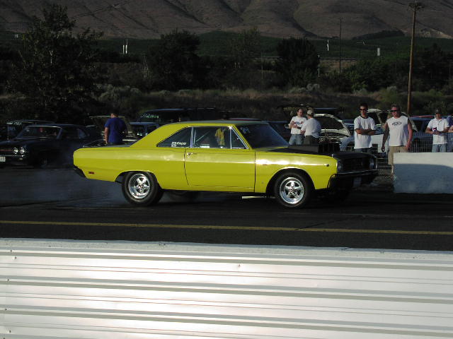 Yellow 1967 Dodge Dart muscle car, side view, black hood, drag strip