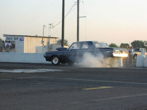 1981 Ford Bronco - Drag car performing a burnout at a race track with a snack bar visible in the background.