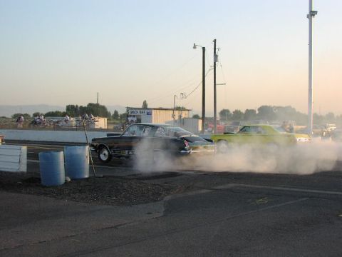 1981 Ford Bronco - Two cars create smoke screens during a burnout competition at a drag strip.