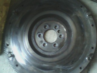 2002 Chevrolet Camaro - A metal flywheel with visible bolt holes and gear teeth is shown with a SuperMotors.net logo.