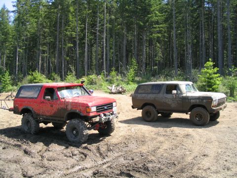 1979 Ford Bronco - Two off-road ready Ford Broncos are covered in mud after a day of driving through the forest.