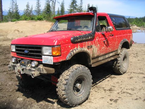 1979 Ford Bronco - This red SUV, likely a 1987 Ford Bronco, is equipped for off-road adventures with a snorkel and large tires.