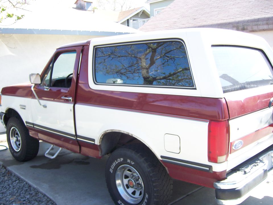 Rear quarter of a red and white Ford Bronco in a driveway