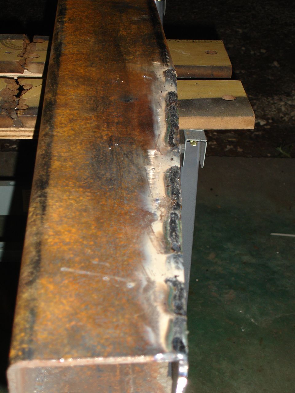Welded metal beam with rust and Supermotors.net logo