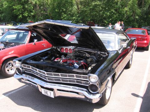 1989 Ford Mustang - A black 1967 Ford Galaxie is parked with its hood open, revealing the engine and a prominent chrome grille.