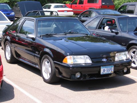 1989 Ford Mustang - A black 1989 Ford Mustang is parked in a lot with other vehicles visible.