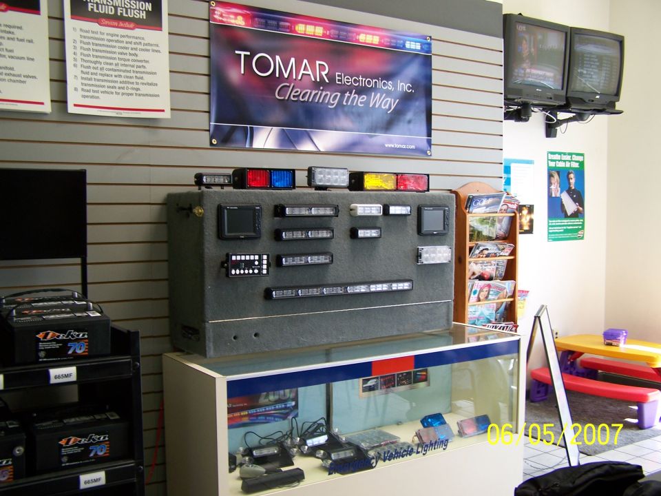 Display of TOMAR Electronics emergency lights and vehicle lighting equipment, with batteries on a shelf and a date stamp of 06/05/2007