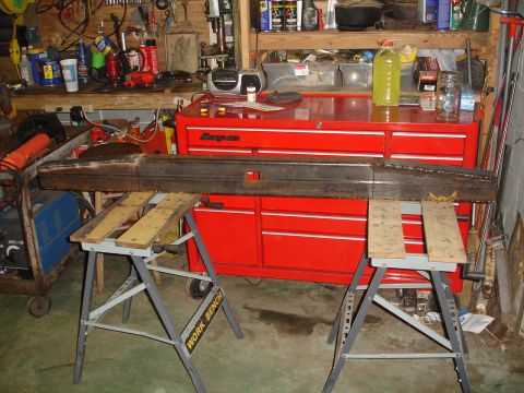 1989 Ford Bronco - Custom fabricated rear bumper resting on sawhorses in a cluttered garage setting.