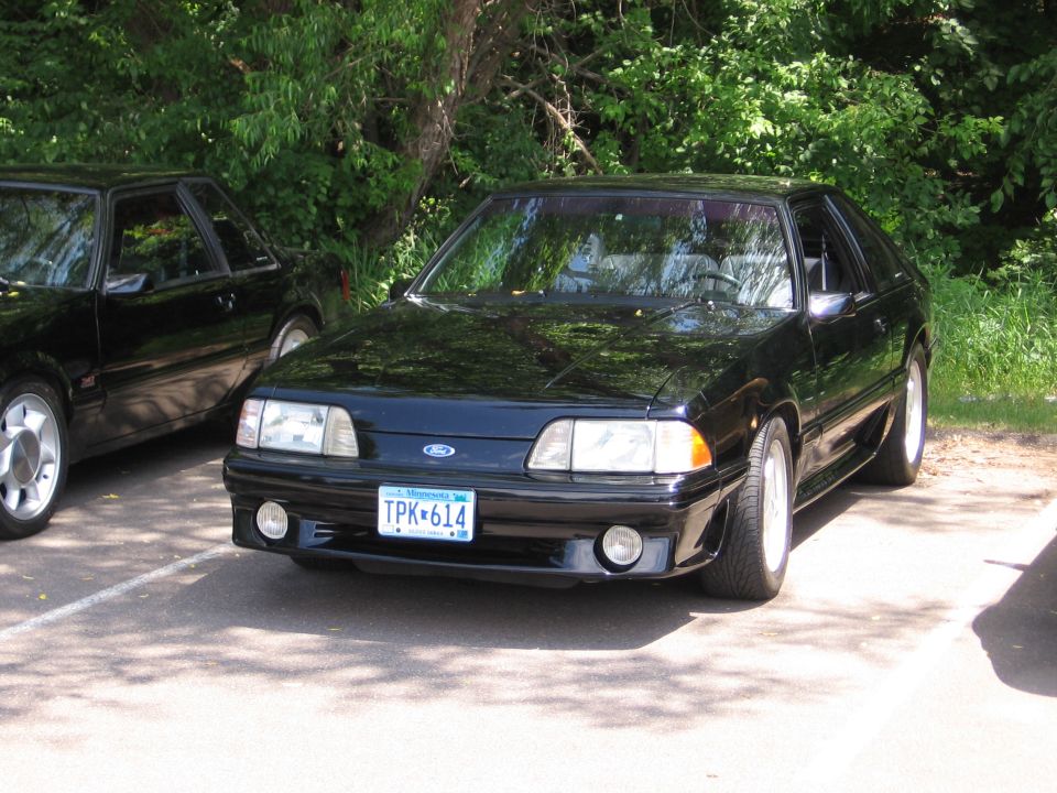 Black coupe parked next to another black car. License plate reads TPK-614