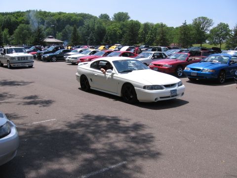 1989 Ford Mustang - A white Ford Mustang is parked in a lot with many other vehicles.