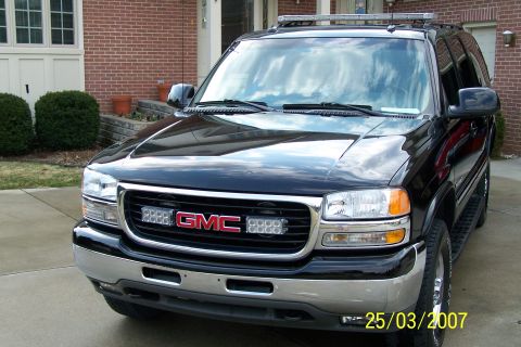2003 Ford Crown Victoria - Front view of a black GMC Yukon SUV, equipped with a light bar on the roof and auxiliary lights on the grille.