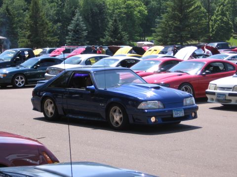 1989 Ford Mustang - A blue 1989 Ford Mustang is parked at an outdoor car show with many other vehicles.