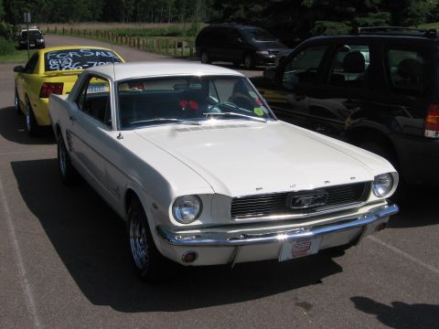 1989 Ford Mustang - A white classic Mustang is parked in a lot, with other vehicles visible in the background.