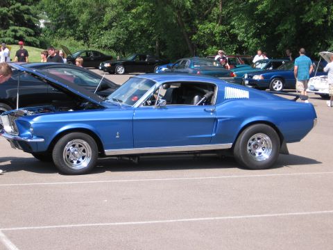 1989 Ford Mustang - A blue classic Ford Mustang is parked at an outdoor car show with other vehicles visible.