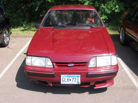 1989 Ford Mustang - Front view of a red 1989 Ford Mustang parked outdoors, showing its distinctive grille and headlights.